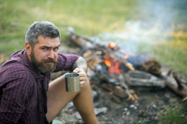 Hipster uzun yürüyüşe çıkan kimse içecek çay kamp ateşi alev