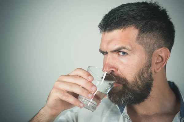 Man med långt skägg hålla vatten glas på grå bakgrund. — Stockfoto