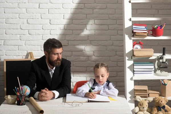 Mann und Mädchen sitzen mit Schulsachen am Schreibtisch — Stockfoto