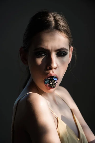 Girl with bug insect brooch in mouth