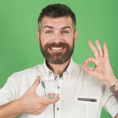 Uzun sakallı adam tutun su bardağı yeşil arka plan üzerinde.