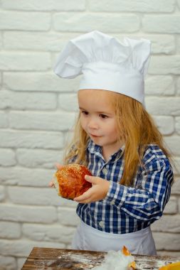 Beyaz tuğla duvara ekmek çörek yiyen çocuk