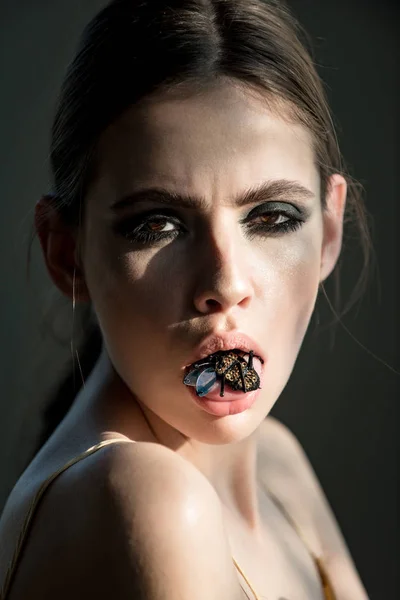 Woman with bug insect brooch in mouth