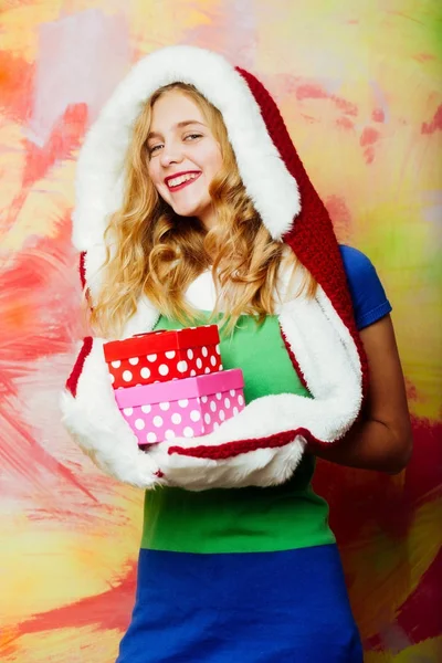 Gelukkig meisje in de rode santa vacht kap met geschenkdozen — Stockfoto