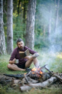 Adam gezgin okumak ve kamp ateşi alev içki