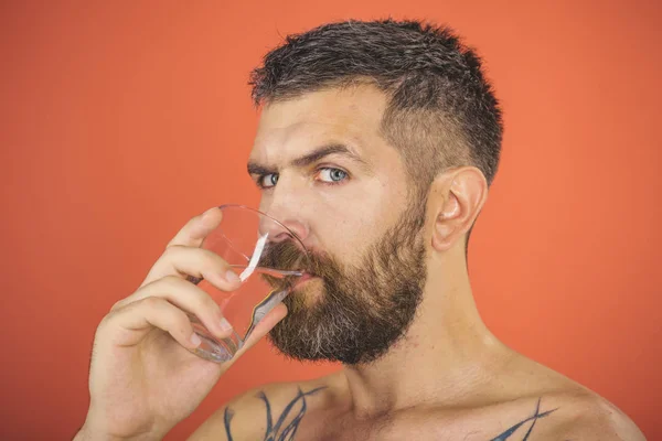 Muž s vousy na tváři pít vodu ze skla — Stock fotografie