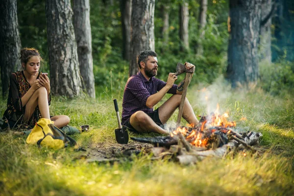 Couple of hikers relax at bonfire in forest