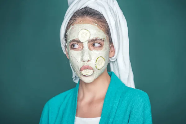 Дівчина з огірком в роті, маска для обличчя на зеленому тлі — стокове фото