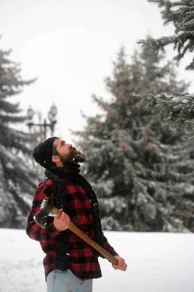 Man met baard in winter forest met sneeuw houdt bijl. — Stockfoto