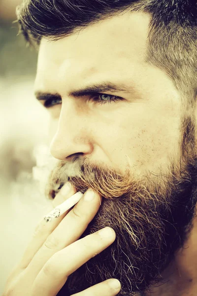 Хмурый бородатый мужчина курит сигарету — стоковое фото