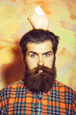 Sakallı adam kafasına pembe seramik kumbara tutan kaşlarını