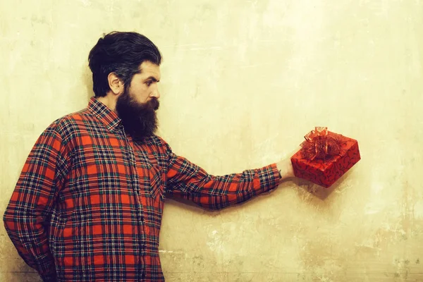 Frown bearded man with long beard holds red gift box