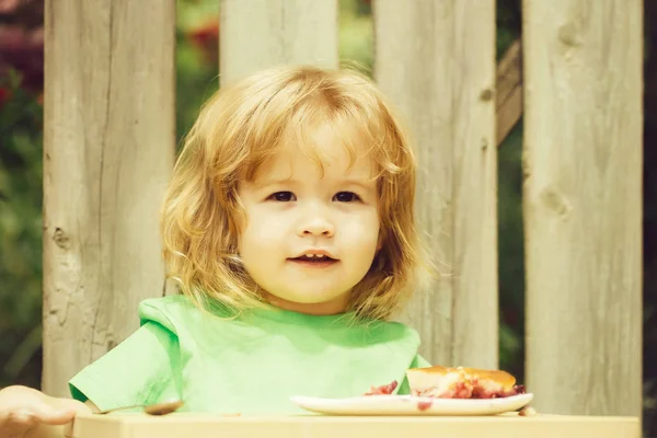 Kleine jongen eten taart in de buurt van houten hek — Stockfoto