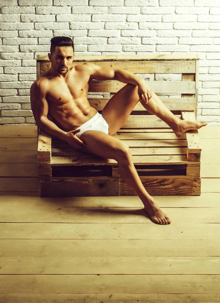 Bonito homem musculoso no banco de madeira — Fotografia de Stock
