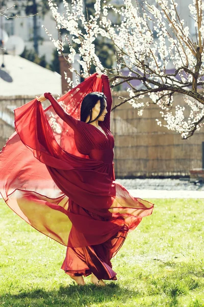 Yakınındaki çiçeği Kırmızı elbiseli kadın — Stok fotoğraf