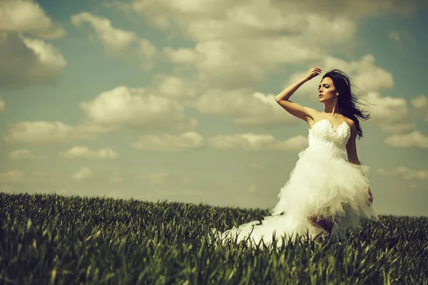 Hübsches Hochzeitsmädchen auf grünem Gras und Himmel — Stockfoto