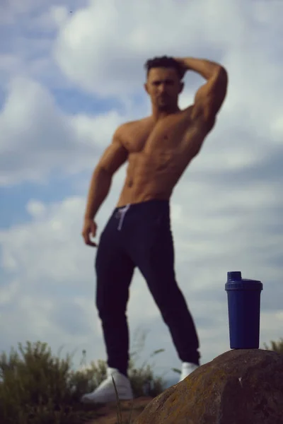 Hombre musculoso posando cerca de botella de agua — Foto de Stock