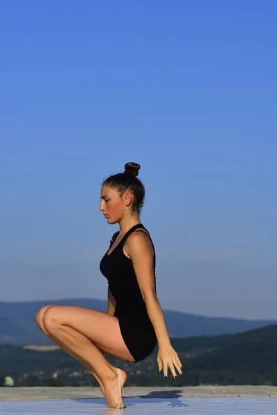 Woman gymnast in black sportswear in yoga pose.