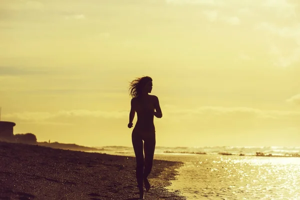 Jolie fille en maillot de bain jaune courant sur une plage de sable fin — Photo