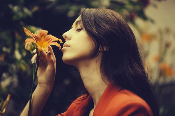 女性はオレンジ色のユリの花を楽しんでいます — ストック写真