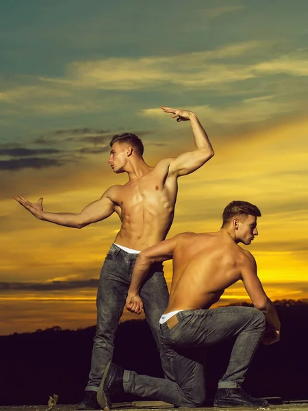 Muskulösa män i solnedgången med lådor — Stockfoto