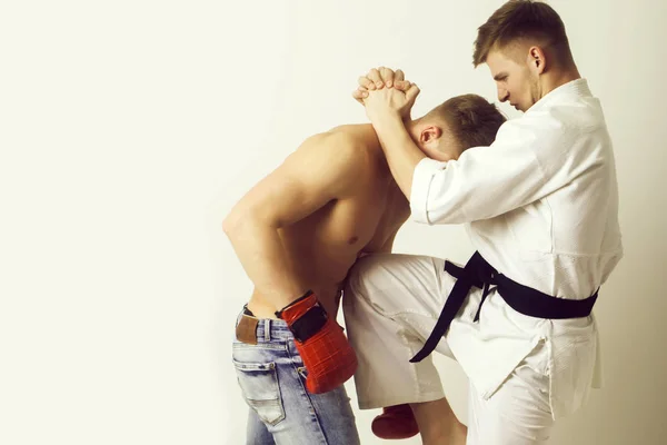 Karate athlete in kimono kicking knee at boxer