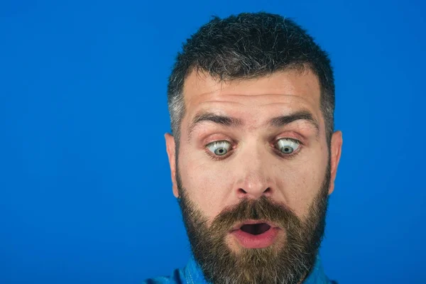 Hipster mies parta yllättynyt kasvot sinisellä pohjalla — kuvapankkivalokuva