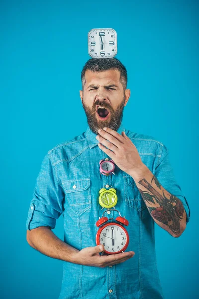 Hombre soñoliento bostezo con la barba mantenga el despertador reloj . —  Fotos de Stock