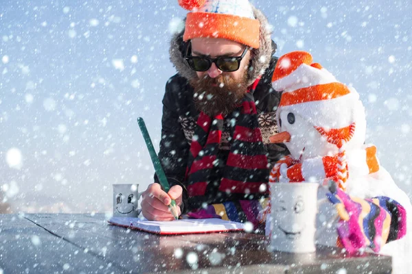 Vánoční muž a sněhulák v klobouku zápis v knize — Stock fotografie