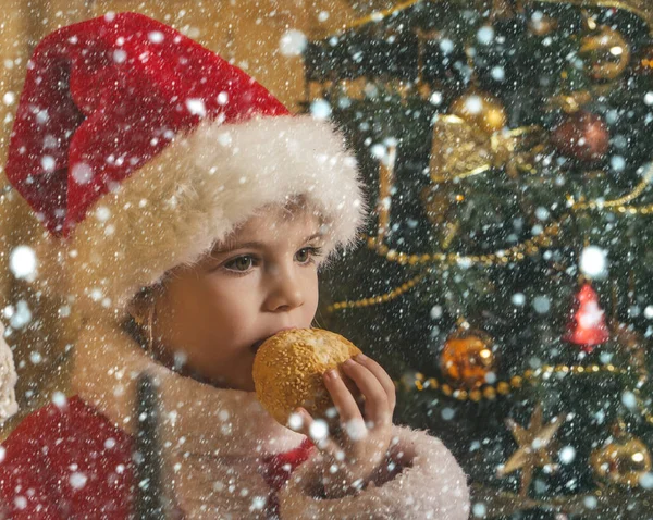 New year small girl in hat eat cookie. — Stock Photo, Image