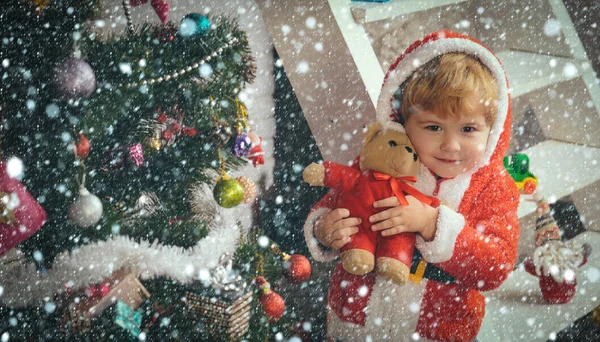 Weihnachtskind oder kleiner Junge im Weihnachtsmantel halten Bären — Stockfoto