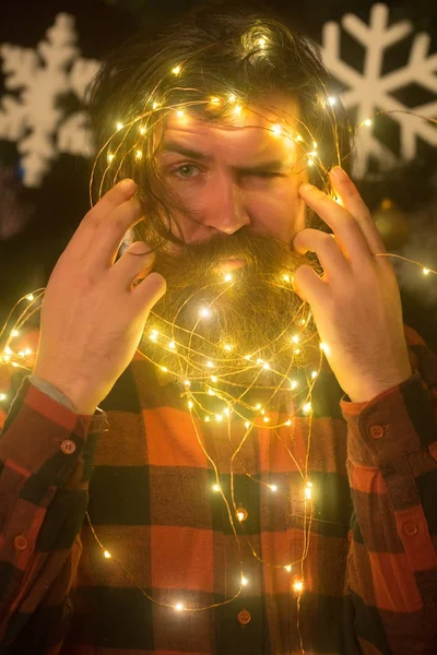 Christmas man with beard on serious face and garland.