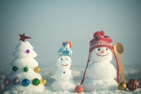 Bonhommes de neige avec des visages souriants dans des chapeaux le jour d'hiver — Photo