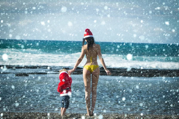 Flicka i baddräkt och pojke bär santa dräkt — Stockfoto