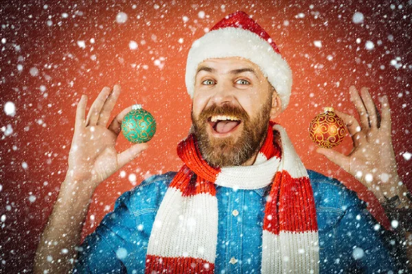 Kerst man houden xmas ballen op rode achtergrond — Stockfoto