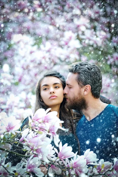Homem beijando menina bonita em árvores florescentes com magnólia — Fotografia de Stock