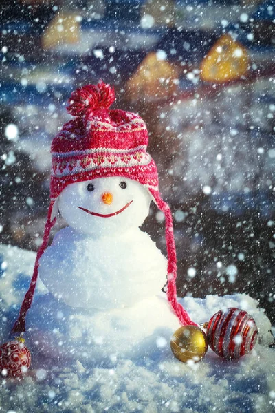 Snowman in red hat on countryside background — Stock Photo, Image