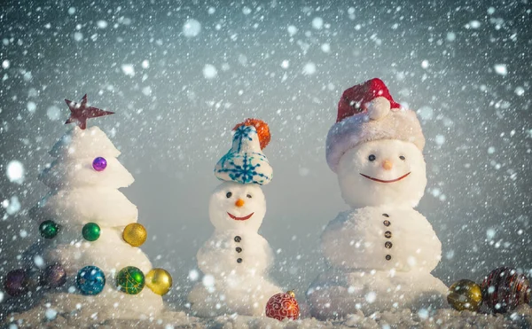 Bonhommes de neige avec des visages souriants dans des chapeaux le jour d'hiver — Photo