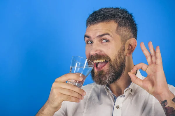 Άνθρωπος με μακριά γενειάδα κρατήστε πατημένο ποτήρι νερού σε μπλε φόντο. — Φωτογραφία Αρχείου