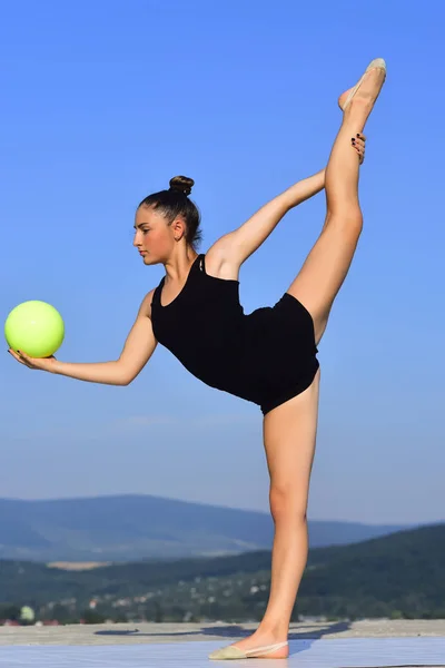 Vrouw gymnast met groene bal op blauwe hemelachtergrond — Stockfoto