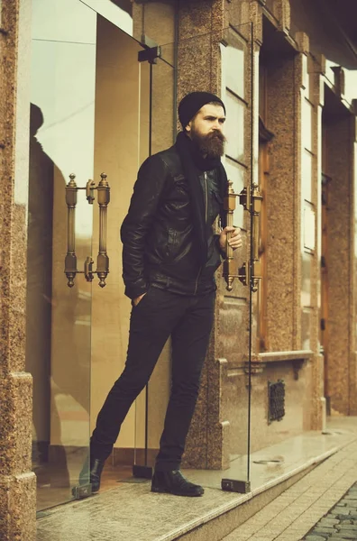 Серйозний бородатий чоловік хіпстер вихід скляні двері в шкіряній куртці — стокове фото