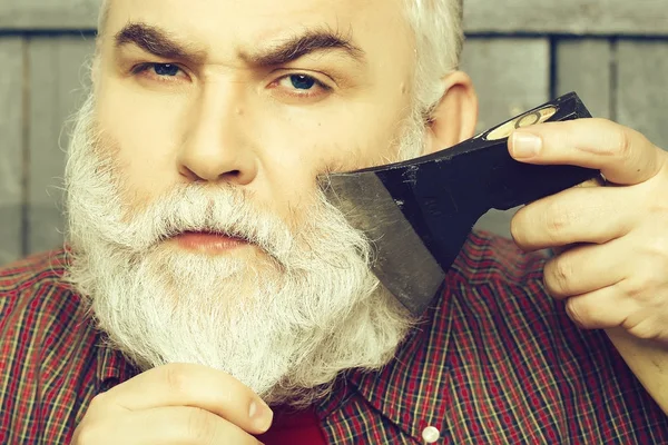 Old man shaving with axe