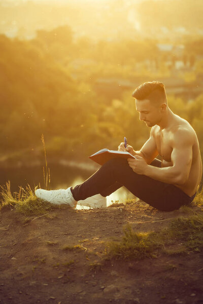 Pensive muscular man with book outdoor