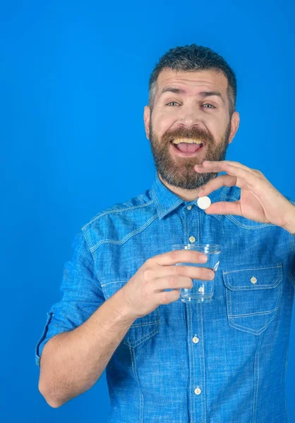 Mies, jolla on parta pidä vettä lasi sinisellä pohjalla, päänsärky . — kuvapankkivalokuva