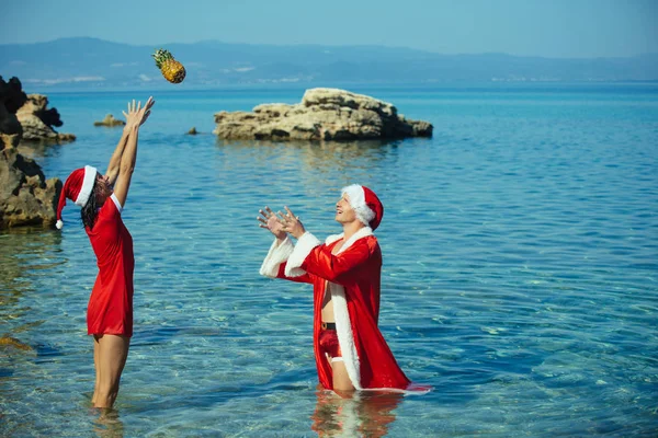 圣诞节夫妇扔菠萝在海滩. — 图库照片