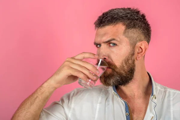 Man med långt skägg hålla vatten glas på rosa bakgrund. — Stockfoto