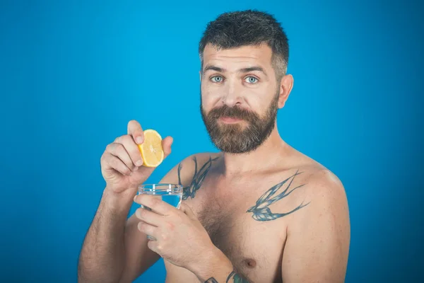 Man met lange baard houden waterglas op blauwe achtergrond. — Stockfoto