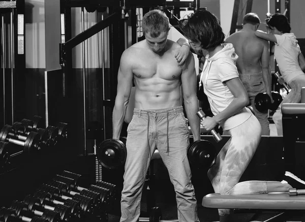 Muscular man and girl at gym with dumbbells — Stock Photo, Image