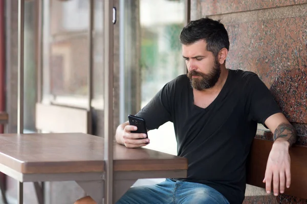 Sakallı adam cep telefonu ile oturup açık kafe — Stok fotoğraf