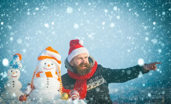 Weihnachtsmann zeigt mit Finger auf verschneite Skulpturen — Stockfoto